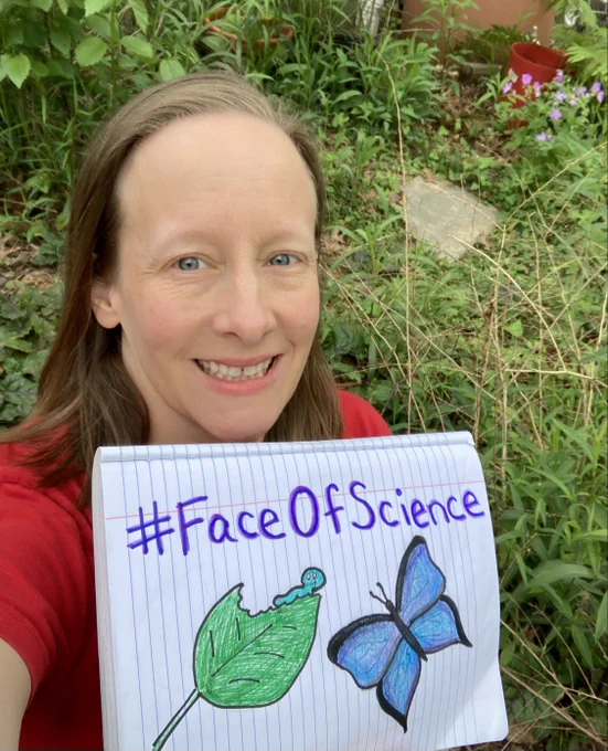 A woman with a red shirt holding a notebook with a sketch of a blue caterpillar and blue butterfly and the hashtag "Face Of Science." She is smiling in front of plants in the background.