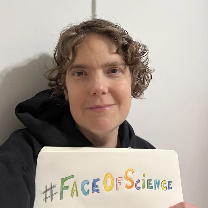 A woman smiling at the camera with a colorful sketch of the hashtag, "Face of Science." 