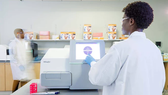 Two individuals in a lab using an Illumina MiSeqDX.