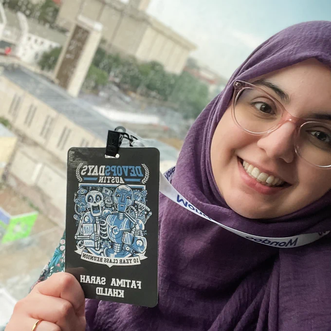 Fatima smiling while holding her conference badge.