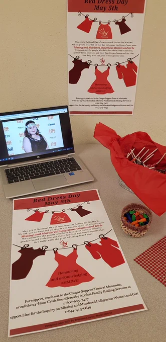 Photo of Emerald MacDonald on computer screen as part of display for Red Dress Day - the National Day of Awareness of Misding and Murdered Indigenous Women and Girls. Poster of red dresses on a clothesline designed by Gr. 12 student Brianna Liness.