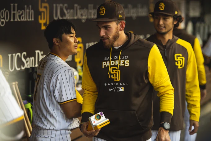 Joe Musgrove walking away holding a Polaroid camera after taking a photo.