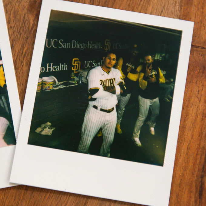 A photo of a Polaroid picture of Manny Machado posing with his arms crossed and Sean Manaea and Nick Martinez in the background. 