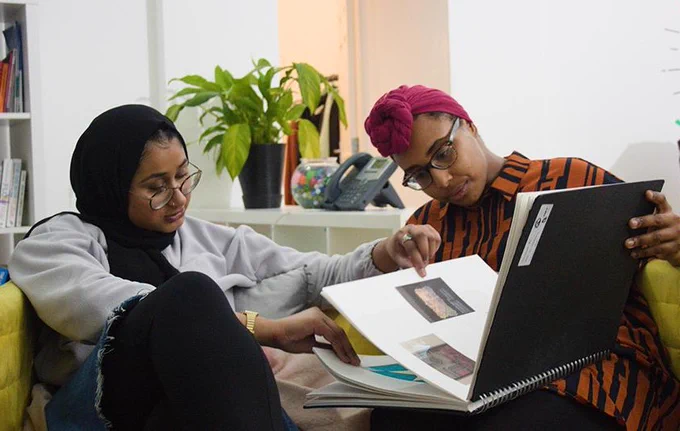 Two people look at a book of images.