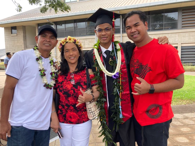 A graduate in a cap and gown with three people.