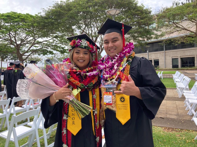 Two students in graduation caps and gowns.