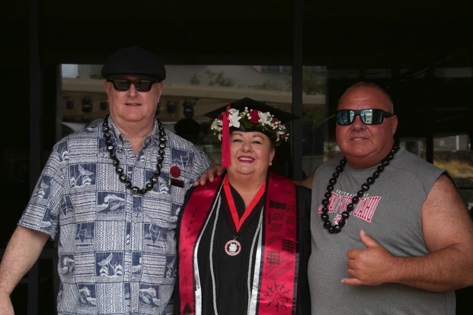 A graduate in her cap and gown with two people.