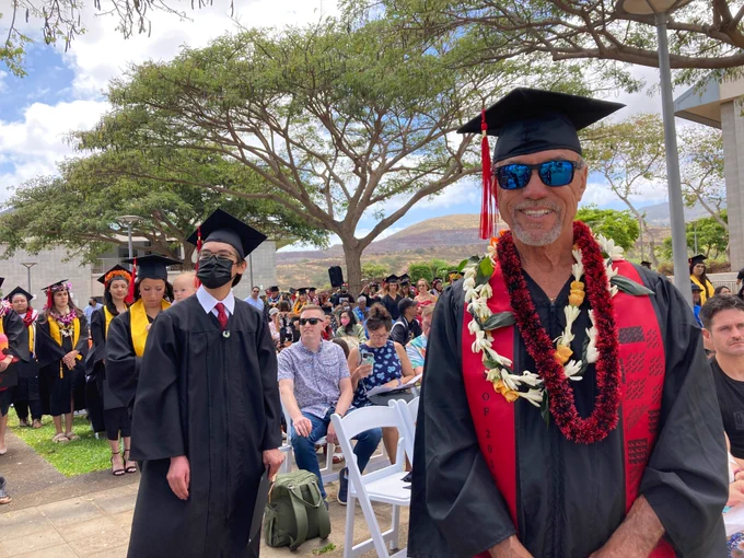 Graduates in their caps and gowns, standing next to their family and friends in the audience.