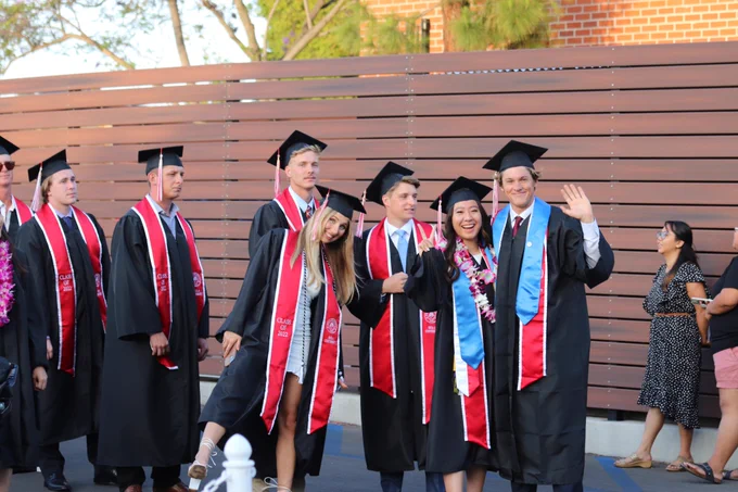 Graduates posing and waving at camera.