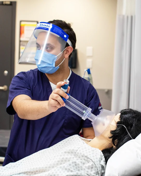 Nursing student demonstrating a health procedure to a mannequin. 