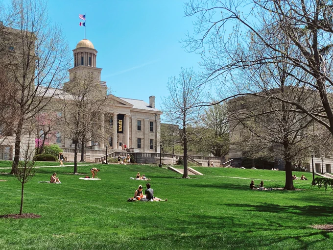 People sit on the lawn of the Pentacrest during a sunny day in May.