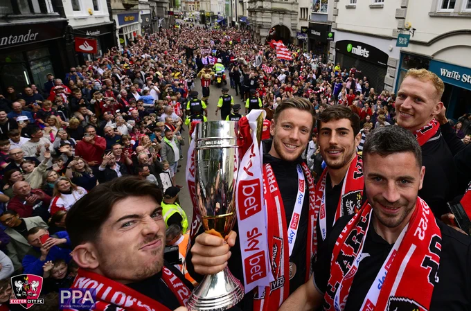 Josh Key, Matt Jay, Sam Stubs, Podge Amond and Cameron Dawson pose with the League Two Runners Up trophy,  in front of supporters in Exeter High Street