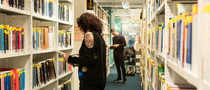 A woman studies a book in a library