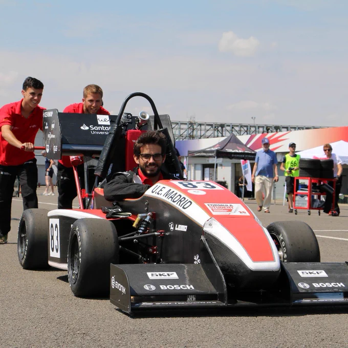 Two team members from UE Madrid push their car across the paddock and on to the scrutineering bay at Silverstone