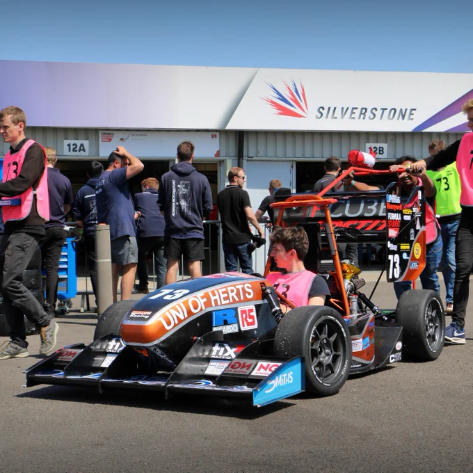 The University of Hertfordshire's car in the sun outside their garage as the team prepare to push it along the Silverstone paddock.
