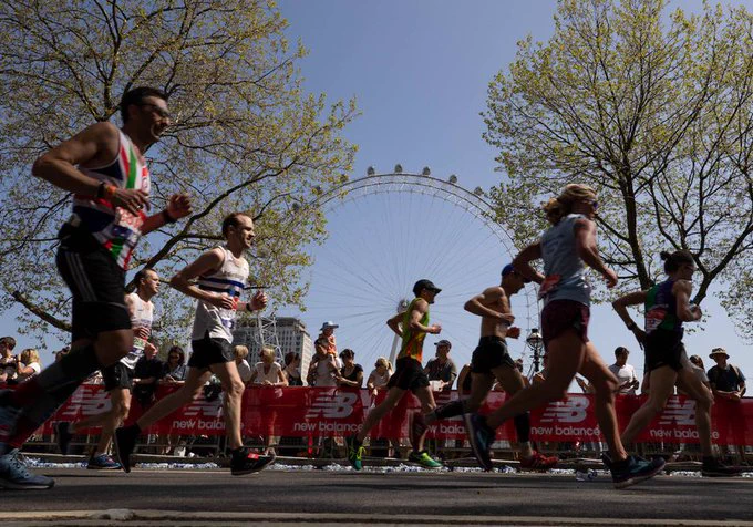 People talking part in the London Marathon running past the London Eye