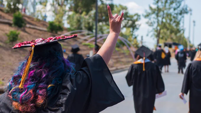 A photo of a college graduate wearing a cap and gown from behind