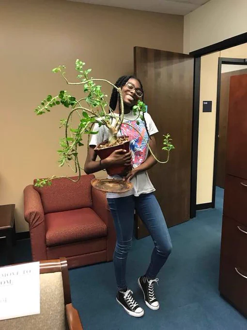 student worker carrying plant
