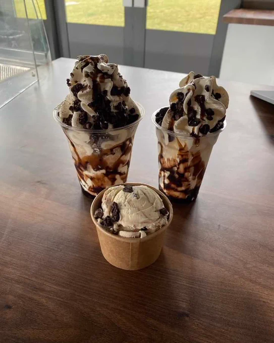 Two sundaes with chocolate sauce and a small tub of ice cream