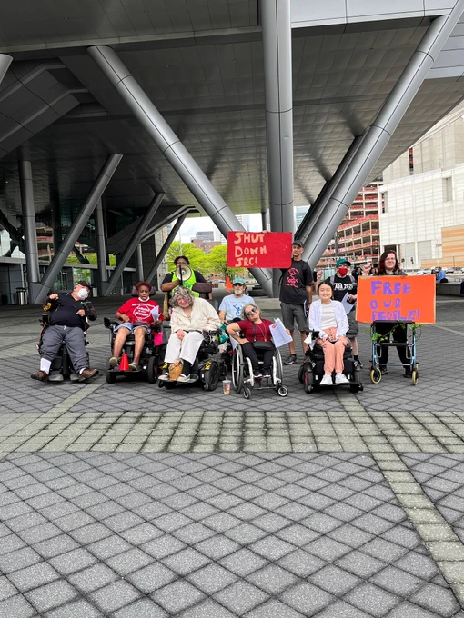A group of ADAPTers holding signs saying SHUT DOWN JRC and FREE OUR PEOPLE