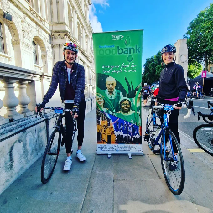 Two cyclists next to foodbank banner