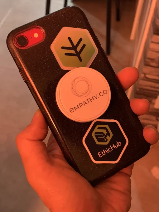 Lado reverso de mi móvil con pas pegatinas de Ethix y EthicHub y en medio, un soporte para sujetar el móvil de Empathy