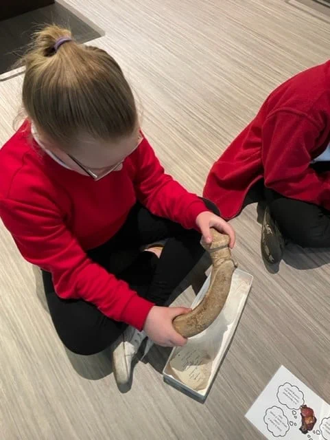 A child holding an object from one of handling boxes.