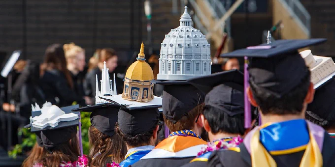 3-D structures of St. Peter's Basilica in Rome, the Golden Dome of the Main Building at the University of Notre Dame, the Sagrada Familia in Barcelona, and Union Terminal in Cincinnati on top of mortarboard graduation caps.