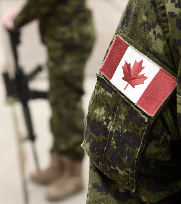 Flag of Canada on the military uniform and soldier with weapon on the background. Canadian soldiers. Canadian Army.