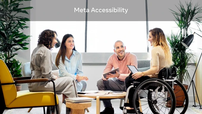 A group of four  coworkers, one of whom is using a wheelchair, gathers around a table for a meeting in an office. A text overlay at the top reads “Meta Accessibility.”