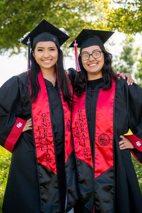 Alison and Jennifer arm in arm in grad gear and first gen stoles