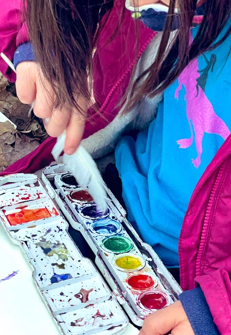 First grader dipping feather into watercolors