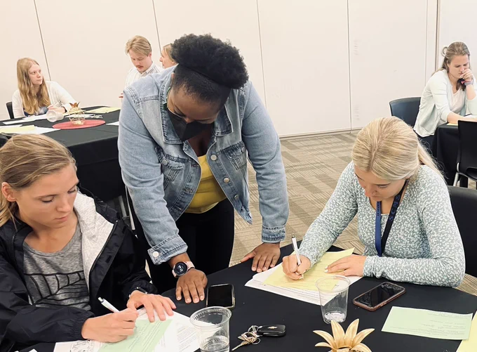 Three adults at a table, writing and looking at papers.