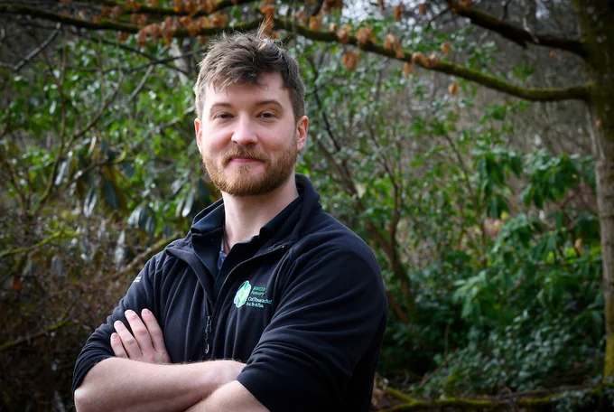 Photo of a Scottish Forestry Woodland Officer in corporate clothing in a woodland setting.