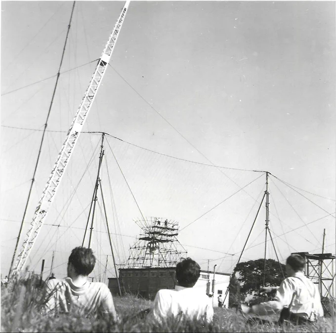 3 men looking on at colleagues working on a telescope at Jodrell Bank