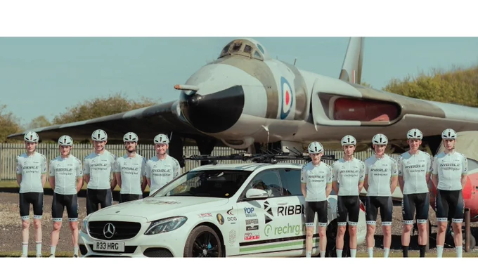 Members of the RIBBL Recharg team stood by a car and in front of a jet.
