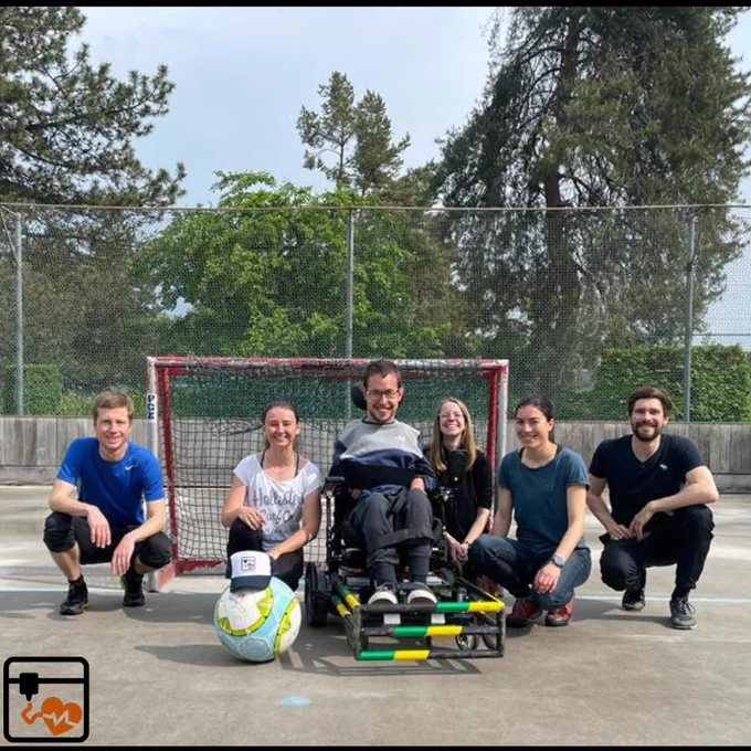 Group picture of the team together with Jérôme in his special wheelchair for powerchair football. The ball is wearing a cool HackaHealth cap. 
