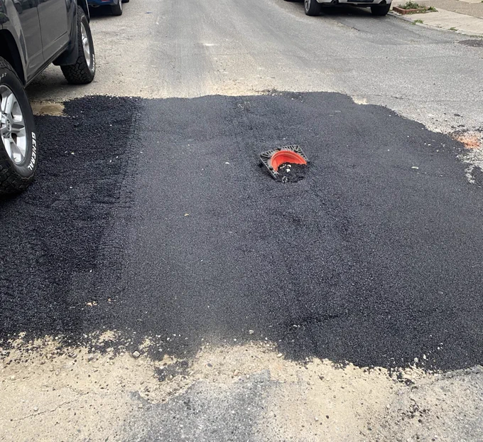 A pit of new asphalt with an upside down cone in the middle of it, submerged in the asphalt.