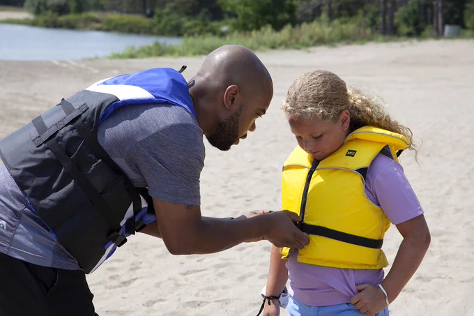 parent zipping up child's pfd