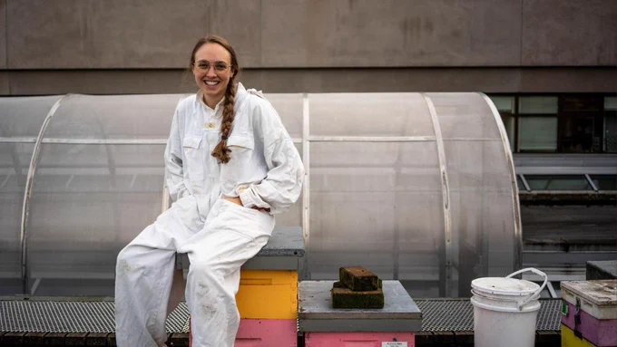 PhD student Abigail Chapman sitting on the roof of the Networks of Centres for Excellence, near the beehives