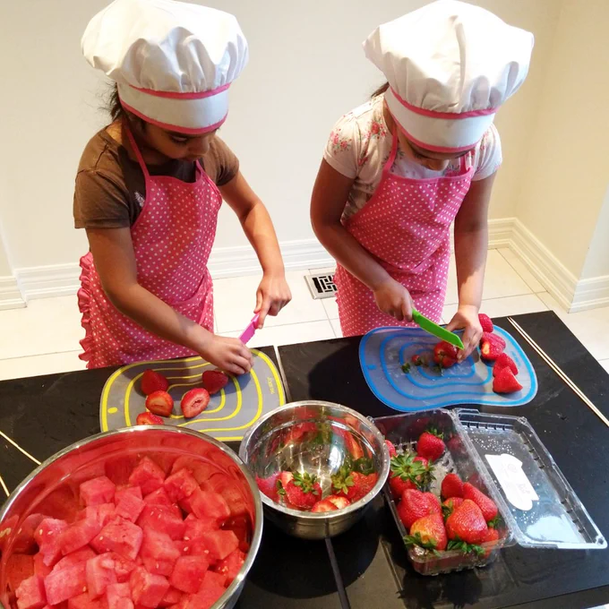Twin sisters preparing fruit kabobs. 