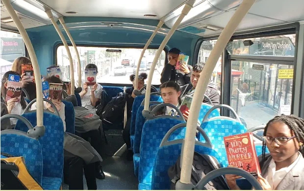 Students on a bus all holding up different book covers