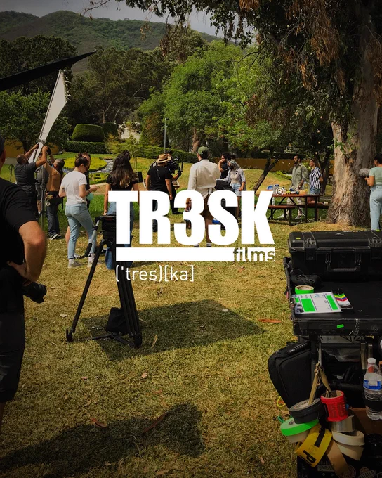 Logotipo de tres ka, casa productora en monterrey, en primer plano, atrás, vemos una filmación en un jardín en un día soleado