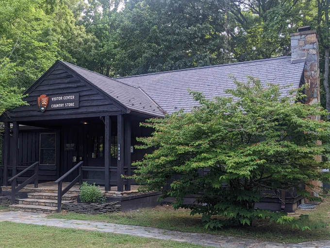 Dark wooden visitor center building at Prince William Forest Park with a stone chimney surrounded by green trees