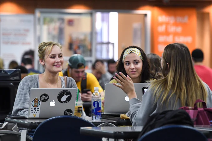 Three WVU students talk to each other while using their laptops in the Mountainlair.