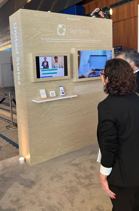 male and female looking at a brown board with Sign-Speak branding and technology. 