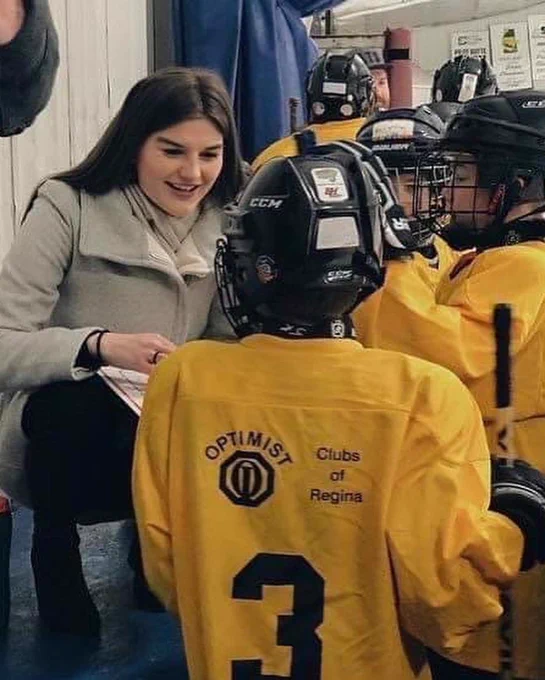 A Métis athlete coaching kids’ hockey to four participants.