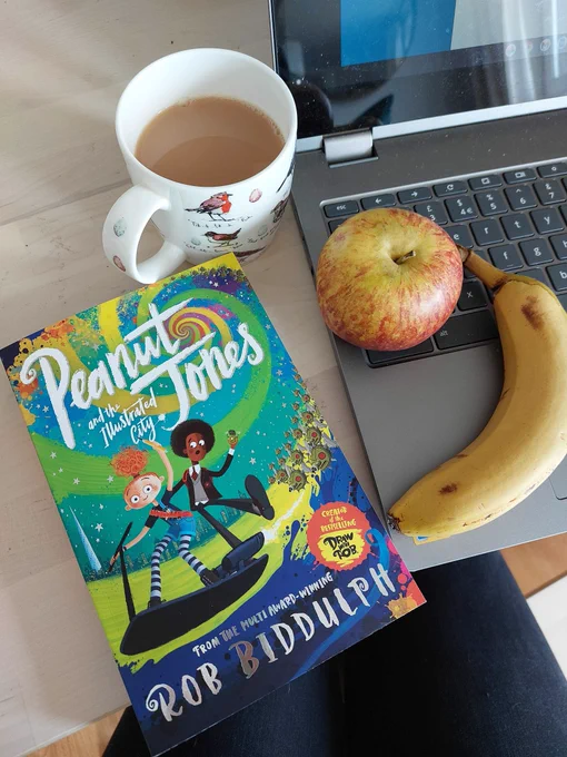 A copy of "Peanut and Jones" by Rob Biddulph with a cup of tea and some fruit