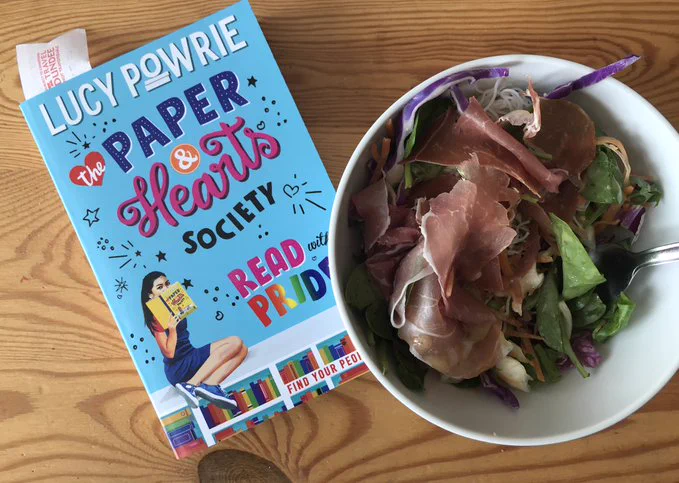 A copy of "The Paper and Hearts Society" by Lucy Powrie and a bowl of salad