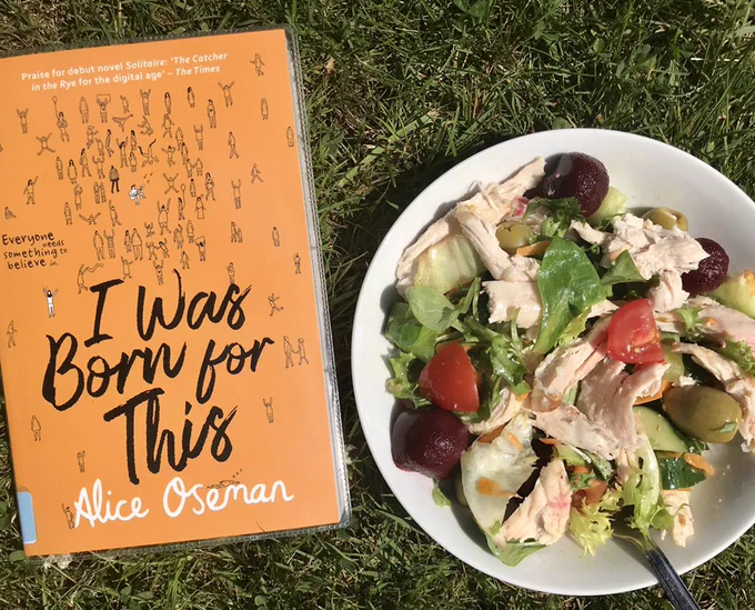 A copy of "I Was Born for This" by Alice Oseman and a bowl of salad